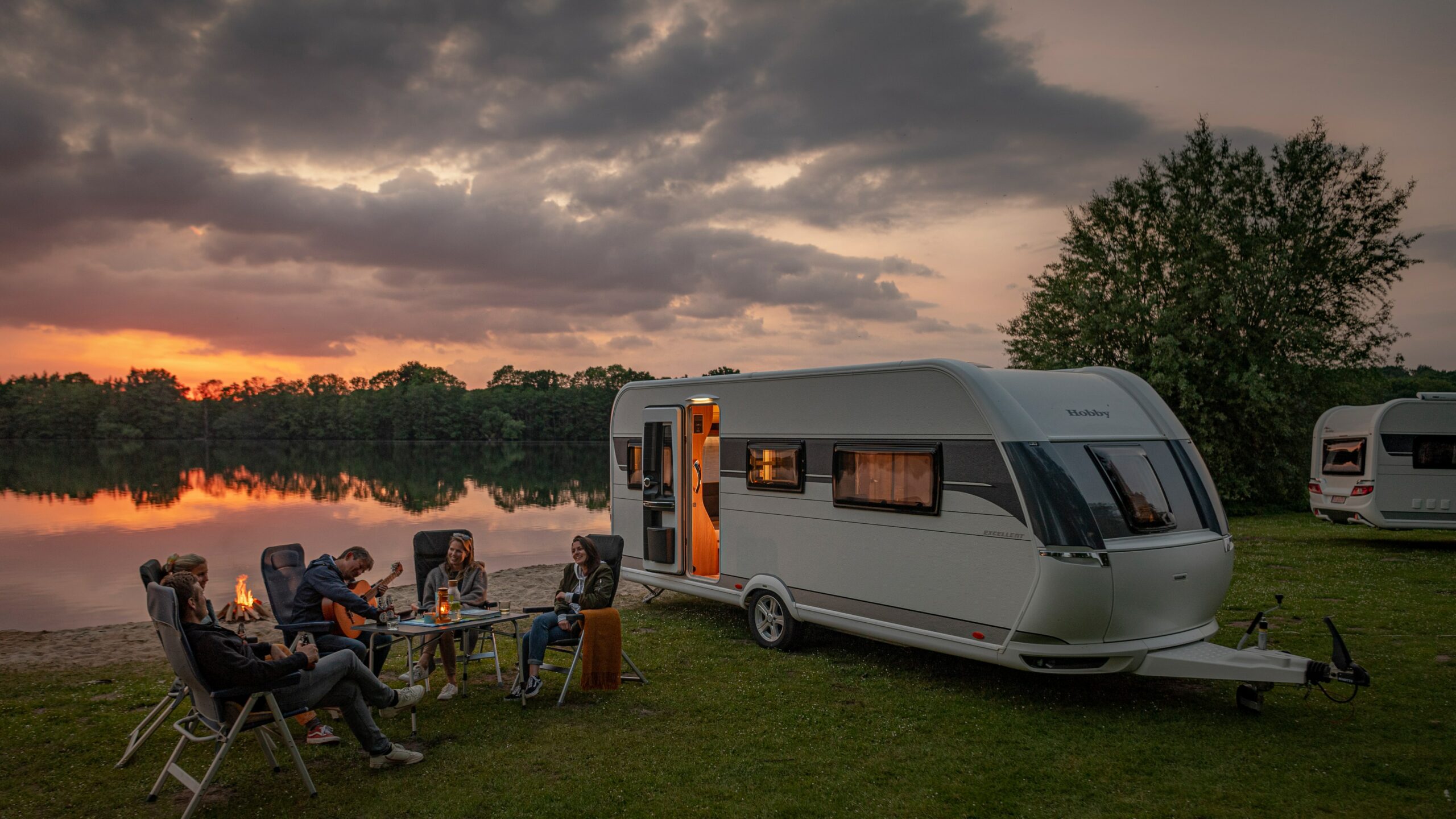 Wohnwagen Hobby am See mit 5 Personen am Tisch. Abendliche Stimmung